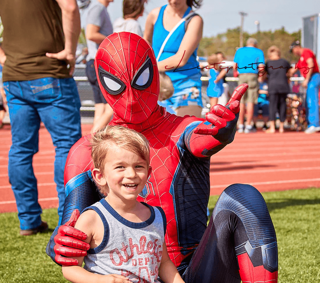 Spiderman poses for the camera with a boy