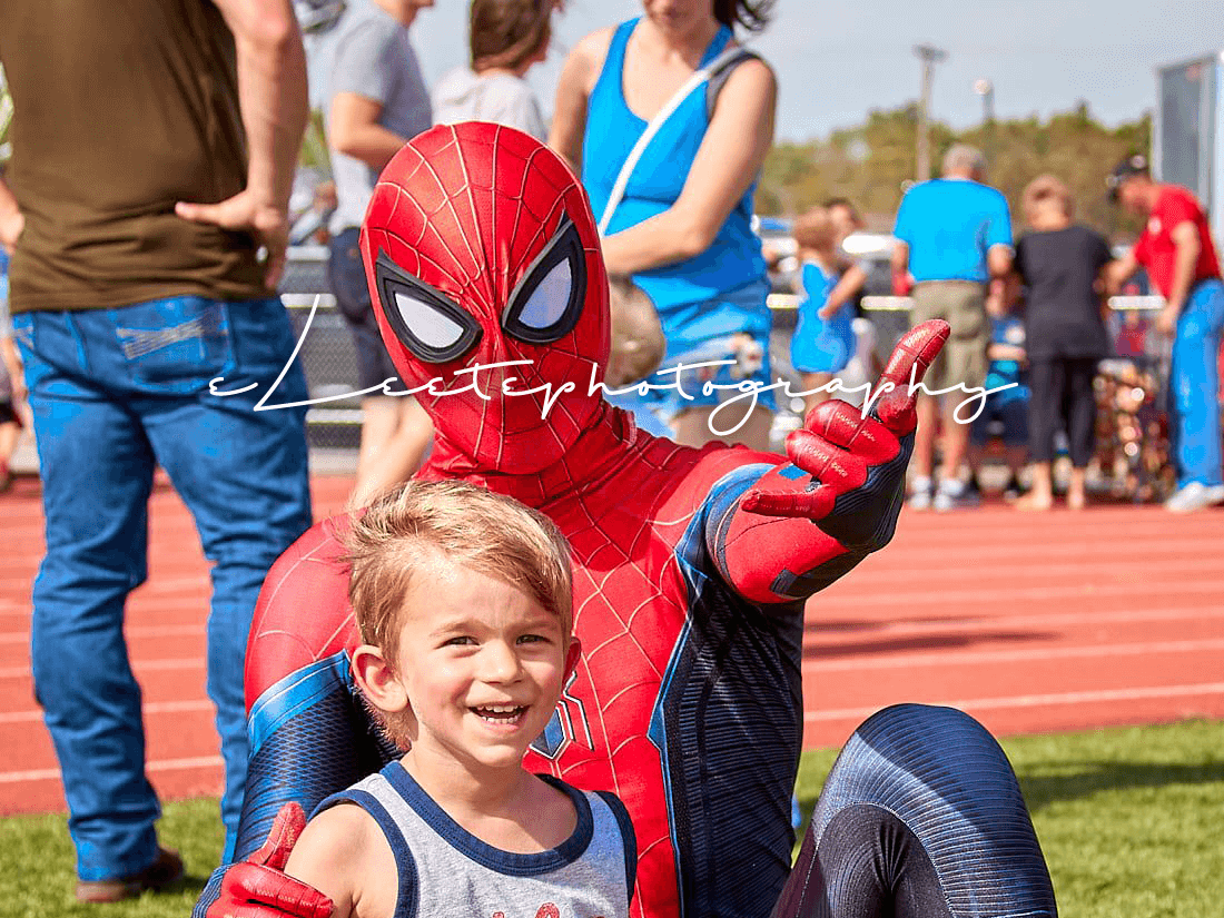 Spiderman poses for the camera with a boy