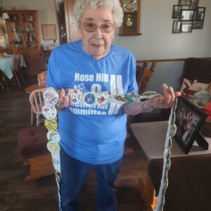 Linot proudly displays her ribbon collection of past button winners, with her favorite being the 2018 design by Jamie Bradza. The button features a cherished portrait of Janis's husband Tom and her grandson Kenneth.